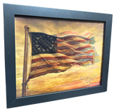 Framed artwork of an American flag against a sunset sky